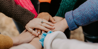 A group of hands touching uniting in a circle.