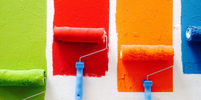A row of different paint colors being placed on a wall (Green, Red, Orange, Blue)