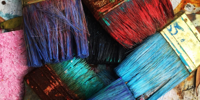 Close up of paint brushes in different colors including blue, purple, red and green.